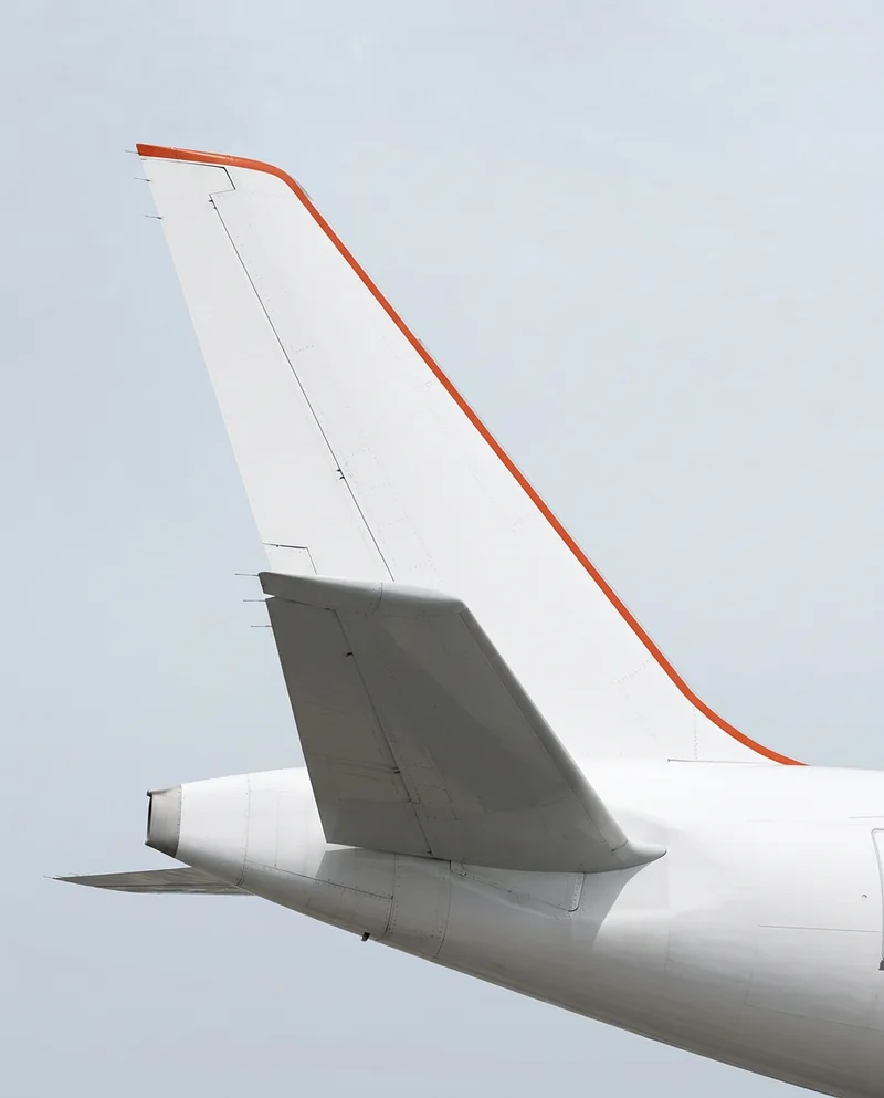 Tail fin of a white passenger jet against a pale sky