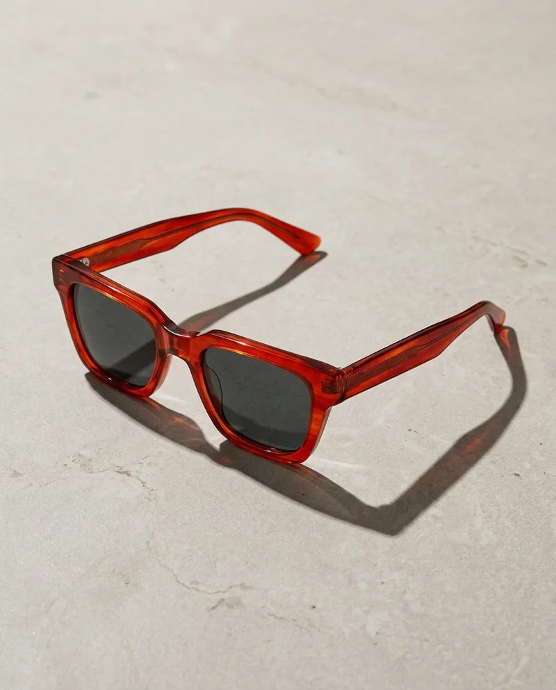 Sunglasses with red frames casting a crisp shadow